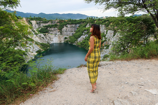 Asian woman wearing a yellow dress looking at Grand Canyon Kiri, also known as Grand Canyon Chonburi, is located in Soi Kiri Nakhon.Originally an old mine, abandoned on the road through Bangkok-Chonburi, the route gradually became more complicated.
