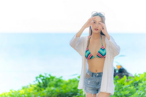 Artistic Beauty Blur Shot of an Asian Woman in Bikini and Beach Outwear, Relaxing and Wandering the Shoreline in Ethereal Style, Embracing Freedom