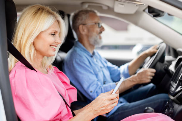 istock Happy elderly woman using smartphone while riding car with husband 1854456207
