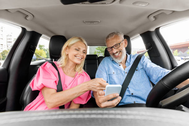 istock Happy senior couple having car trip together, using cell phone 1854457302