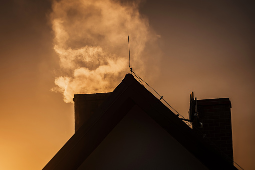 Smoke from the chimney of house during sunset