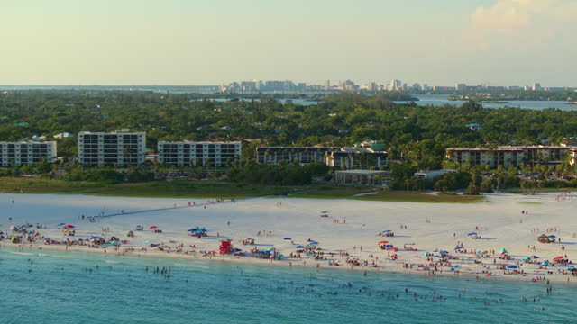 High angle view of crowded Siesta Key beach in Sarasota, USA. Many people enjoying vacations time swimming in ocean water and relaxing on warm Florida sun