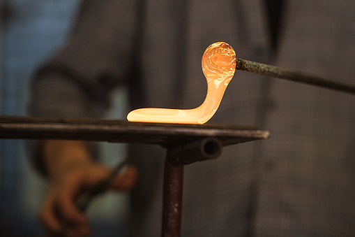 The worker makes a glass ornament in a glass smelter