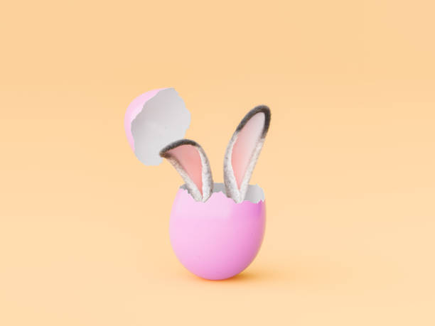 istock Bunny Ears Emerging from a Cracked Pink Easter Egg on Peach Background 1854480540