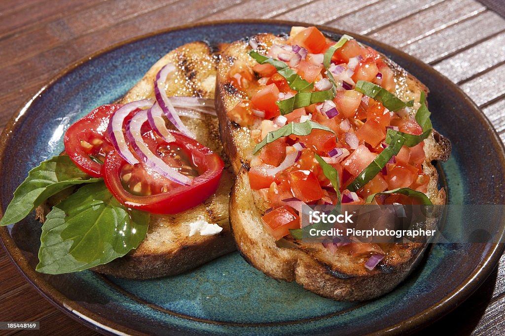 Italian bruschetta Home made Italian bruschetta with chopped tomato, onion and basil on a roasted crunchy slice of bread. Antipasto Stock Photo