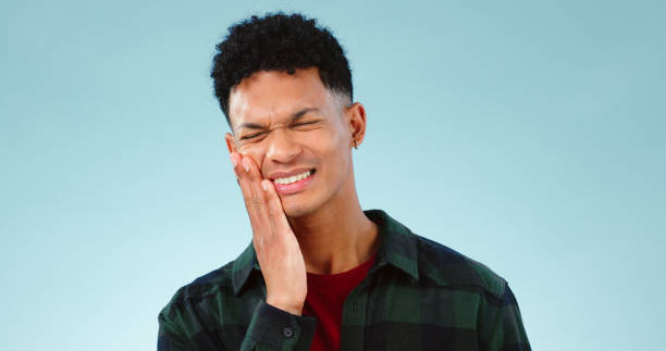 Man, toothache or pain in studio with gum problem, cavity or dental crisis by blue background. Model, face and hands by teeth care for tmj, gingivitis and oral decay or orthodontics help in mockup