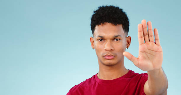 istock Man, hand and stop in studio portrait with forbidden warning, rejection and negative by blue background. Face, palm and hand gesture for defence sign or no, deny and wait for frustrated in mockup 1854491646