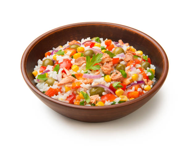 Salad of tuna, rice and vegetables in a terracotta salad bowl isolated on a white background. stock photo