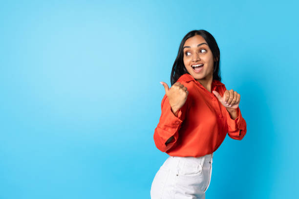 istock Excited Indian Lady Pointing Thumbs At Copy Space, Blue Background 1854526359