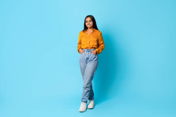 Indian lady standing full length with hands in pockets, studio
