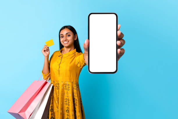 istock indian woman shopaholic holds cellphone displaying empty screen, blue background 1854529084