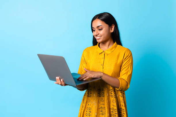 istock Happy young Hindu lady using her laptop computer, blue background 1854529090