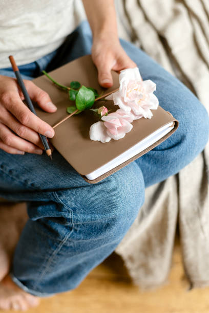 istock Woman holds a notepad and a pink rose. 1854533415