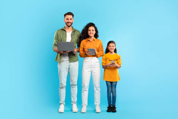 istock European family of three using different gadgets laptop, tablet computer and smartphone, standing over blue background 1854553629