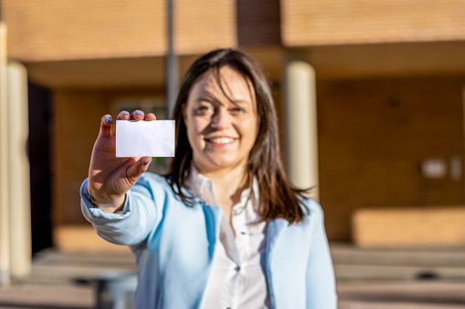 Woman in formal wear showing a business card on the street