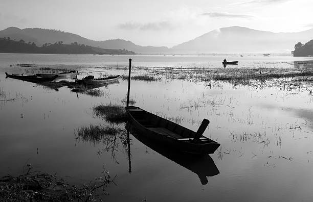 The quiet lake in early morning with black & white tone, fishermen make living on there, boat reflect on surface water