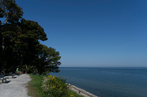 Looking out over Lake Ontario, there are people relaxing beside the lake at Niagara on the Lake, Ontario, Canada.