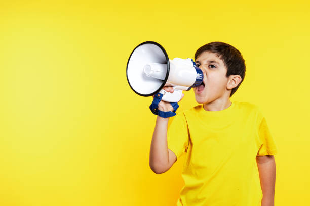 istock Energetic Boy in Yellow Shouting into Megaphone on Matching Background 1854605966