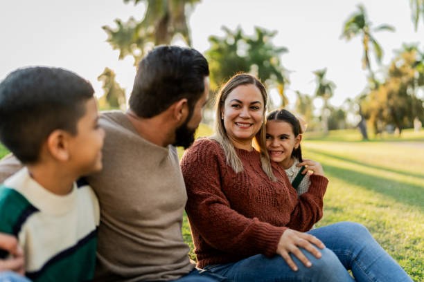 istock Family talking sitting on ground in public park 1854606512