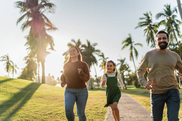 istock Parents running with their daughter in public park 1854607032