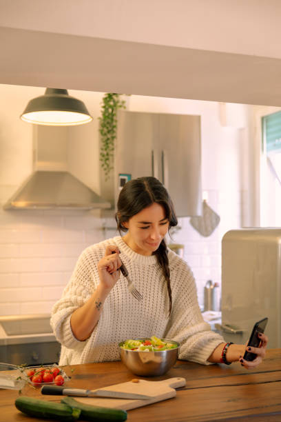 istock Young woman eating and using smartphone 1854609167