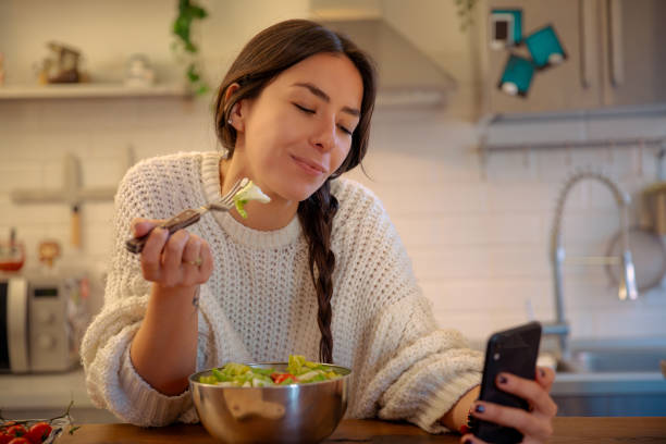 giovane donna che mangia e usando lo smartphone - italian culture women looking at camera cheerful foto e immagini stock