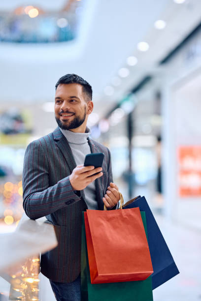istock Happy man using mobile phone while shopping at the mall. 1854616670