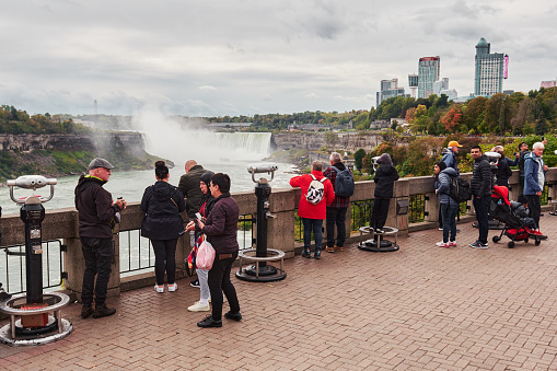 Niagara Falls, Ontario, Canada. A group of tourist enjoying the view of the Horseshoe  falls and the big hotels of Niagara Falls City from The Grand View Observation Dock