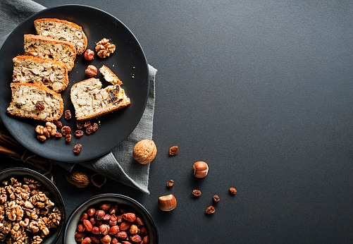 Tasty traditional homemade biscotti biscuits on black table background. Delicious cantucci cookies with nuts and raisin.