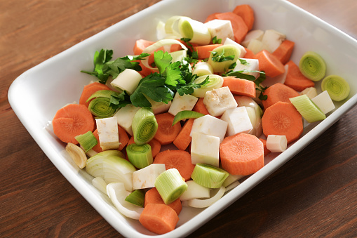 French mirepoix or German Suppengrun (soup greens), raw mixture of diced vegetables with carrots, leek, celery and onion in a white bowl, base for stock, soup, stew or sauce, selected focus