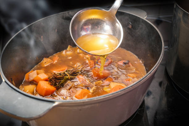 istock Clear broth is poured with a ladle into a casserole pot with steaming vegetables like carrot, onion, celery, leek and herbs, cooking a delicious sauce, soup or stew, copy space 1854652829