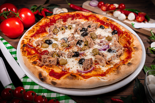 Pizza with tuna and red onion wooden background
