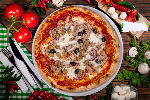Pizza with tuna and red onion wooden background