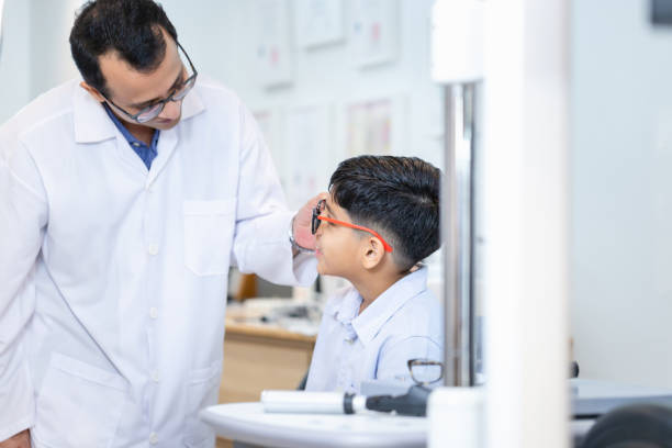 istock Indian child choosing eyeglasses in optics store, Boy doing eye test checking examination with optometrist in optical shop, Optometrist doing sight testing for child patient in clinic 1854664721