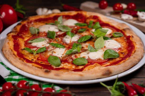 istock Caprese pizza tomatoes, mozzarella and basil on light wooden table 1854667965