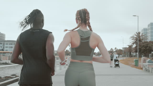 Couple of friends, fitness and running by beach for exercise, workout and cardio health with body wellness and energy. Young sports people or runner training by ocean or on the promenade for support