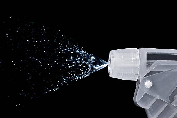 Macro of a bottle nozzle spraying water stock photo