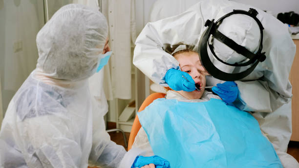 nahaufnahme eines mädchens im overall mit offenem mund auf einem stomatologischen stuhl liegend - mouth open human teeth doctor dental drill stock-fotos und bilder
