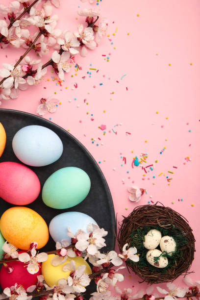 istock Happy Easter. Colorful Easter chocolate eggs with cherry blossoms on pink background. Greeting card or banner. Vertical photo 1854705188