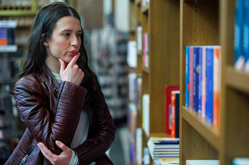 Young Woman Engaged in the Art of Book Selection at a Quaint Bookstore
