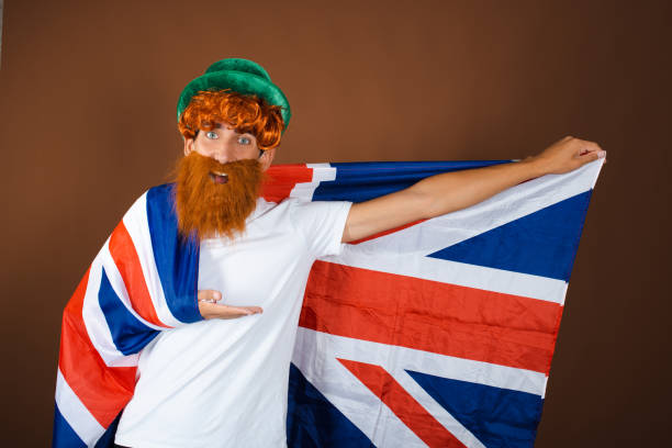 istock St.Patrick 's Day. Funny guy in a leprechaun costume posing on a brown background. 1854724833