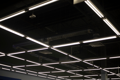 Lamps on the ceiling. Light in the building. Fluorescent lamps in a large room. Large ceiling.