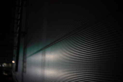 Blinds in the dark. Ribbed wall Horizontal lines texture. Building details in the dark.