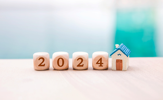 New year 2024 concept, wooden cube with number and miniature house with space on blurred background, new year celebration