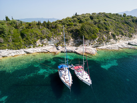 Two sailboats anchored in a magnificent bay on Meganisi island, Greece. The sea is crystal clear, the colors are amazing- blue, green and turquoise, it's a beautiful and sunny summer day.