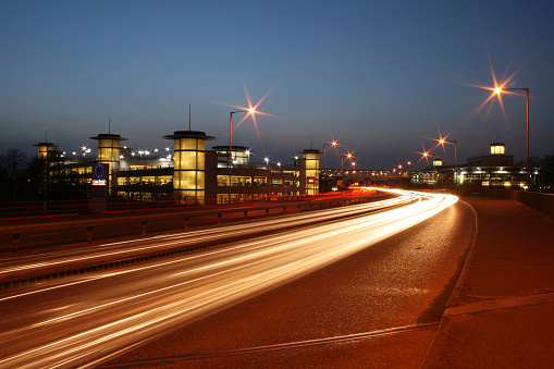 Long exposed traffic light trails with Ashford International Station and car park in background at night, UK, 28 March 2011.