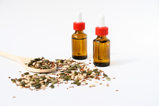 Oil bottles with seeds on white background.