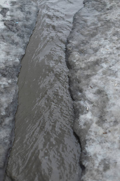 istock Dirty water flows on asphalt. Flow of water along road. Cloudy liquid. 1854805586