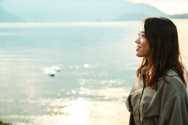 istock Beautiful young woman relaxing at lake side 1854836331