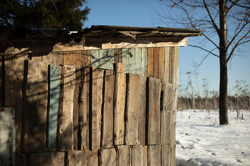 Plank shed. The village in winter. Wooden building. Snow on the roof of the house.